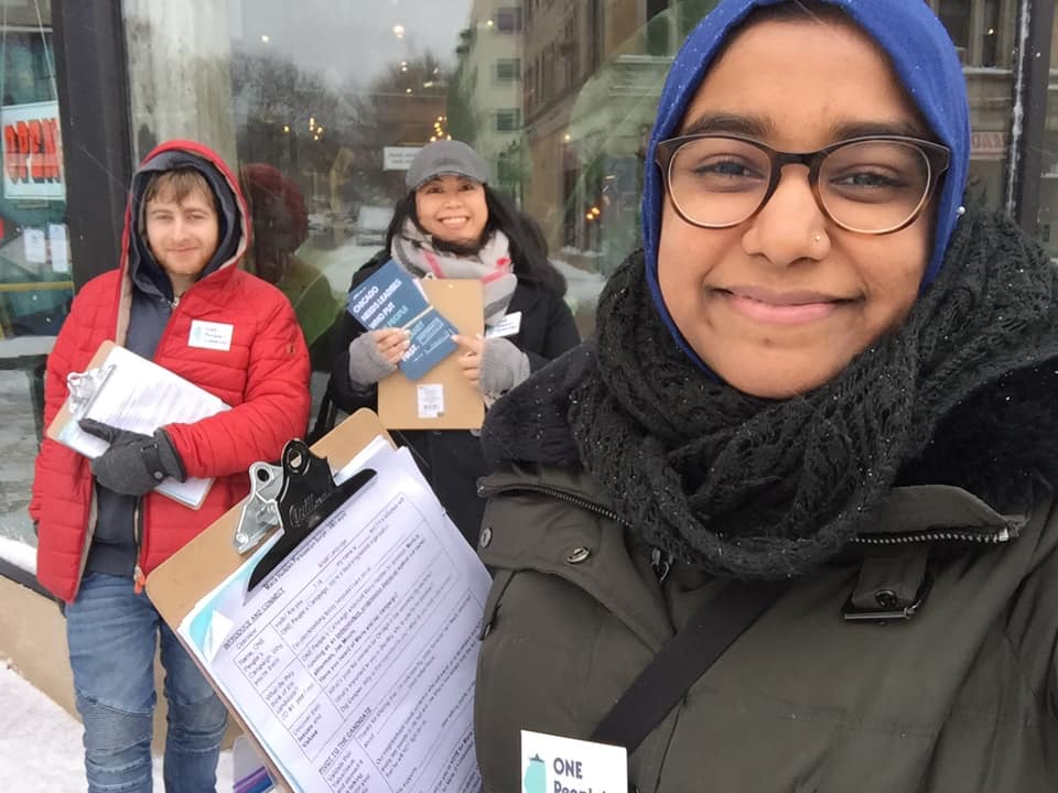 Image showing 3 One People's Campaign canvassers standing in front of a store holding clipboards.